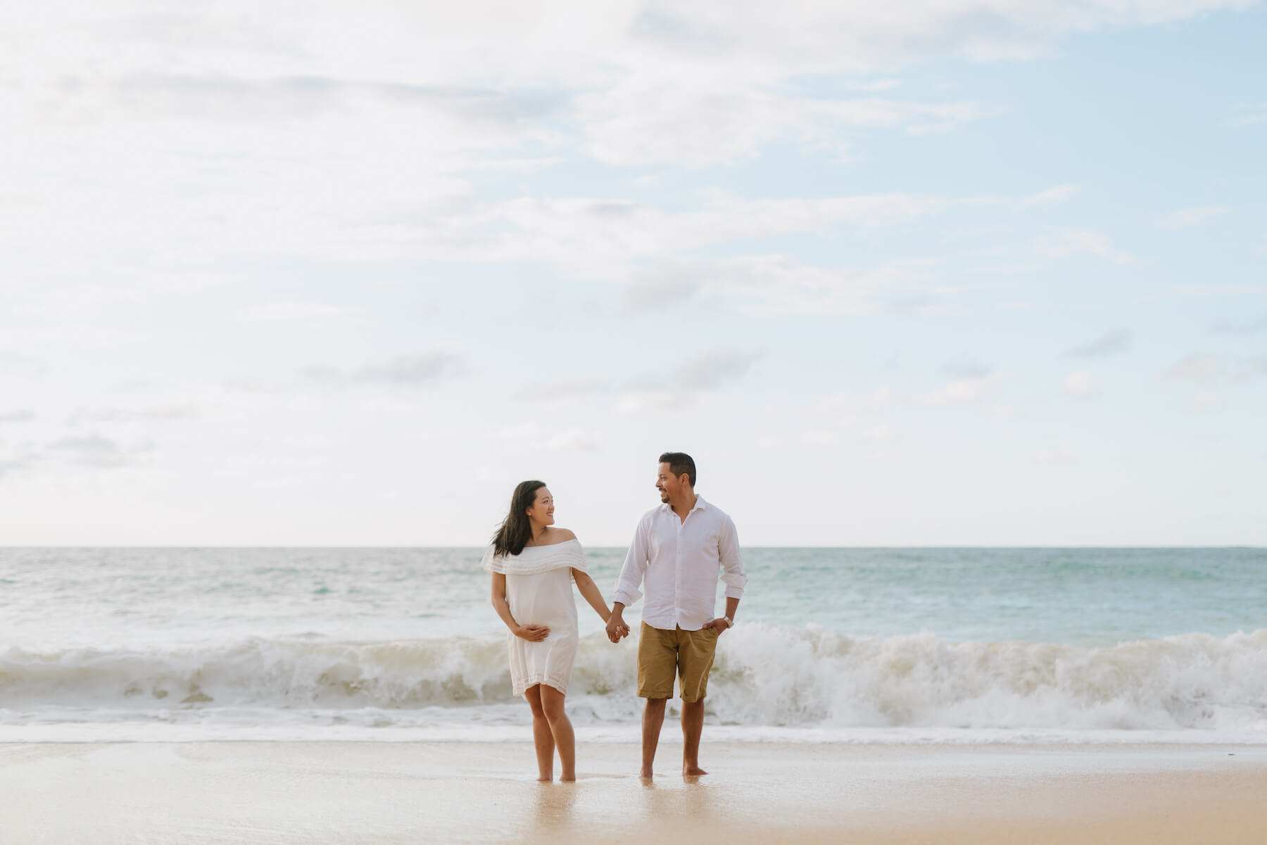 pregnant couple standing on the beach in Maui, Hawaii
