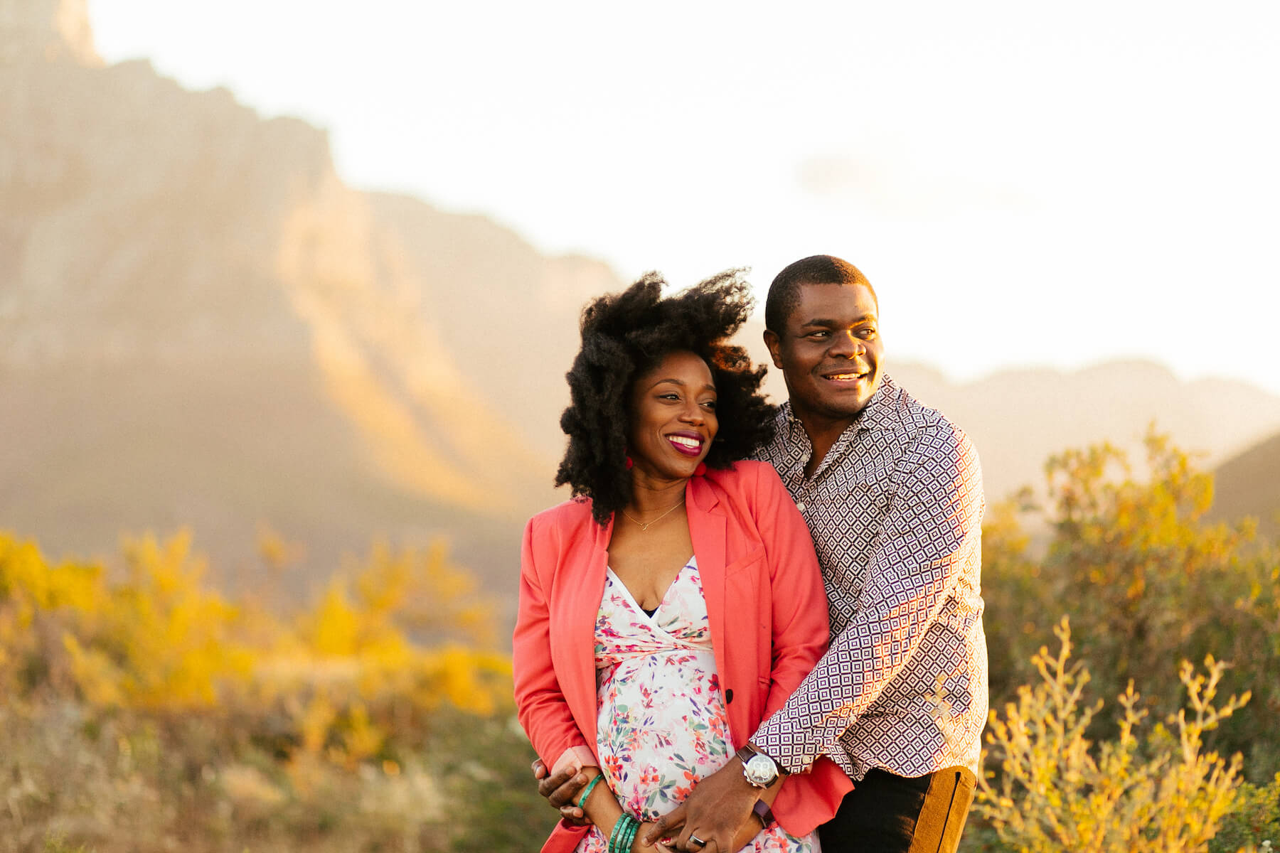 pregnant couple holding each other in a field in Cape Town, South Africa