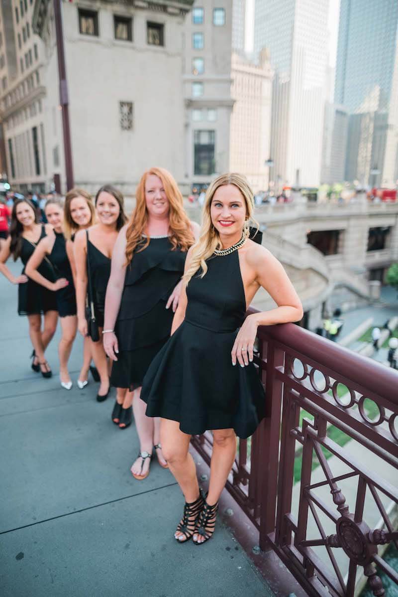 Six female friends on a bachelorette trip together standing one behind another on a bridge in Chicago, USA