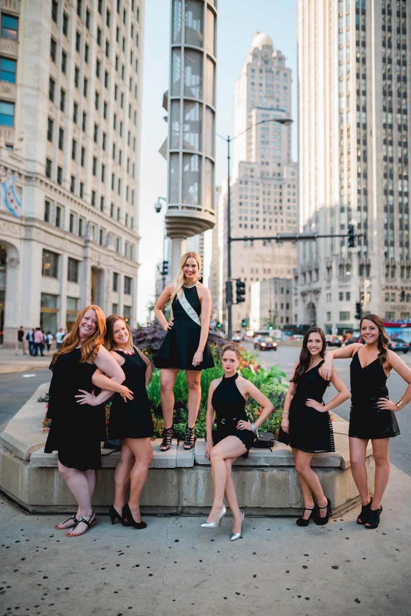 Six female friends on a bachelorette trip standing in a street meridian area together in Chicago, USA