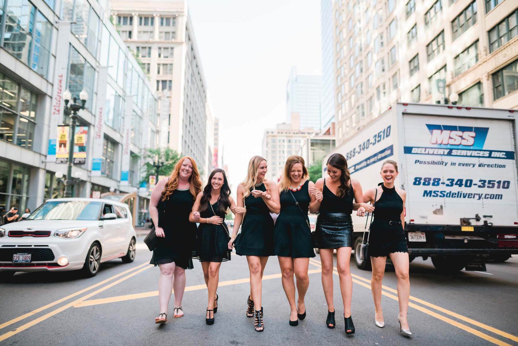 Six female friends walking together down a street on a bachelorette trip in Chicago, USA
