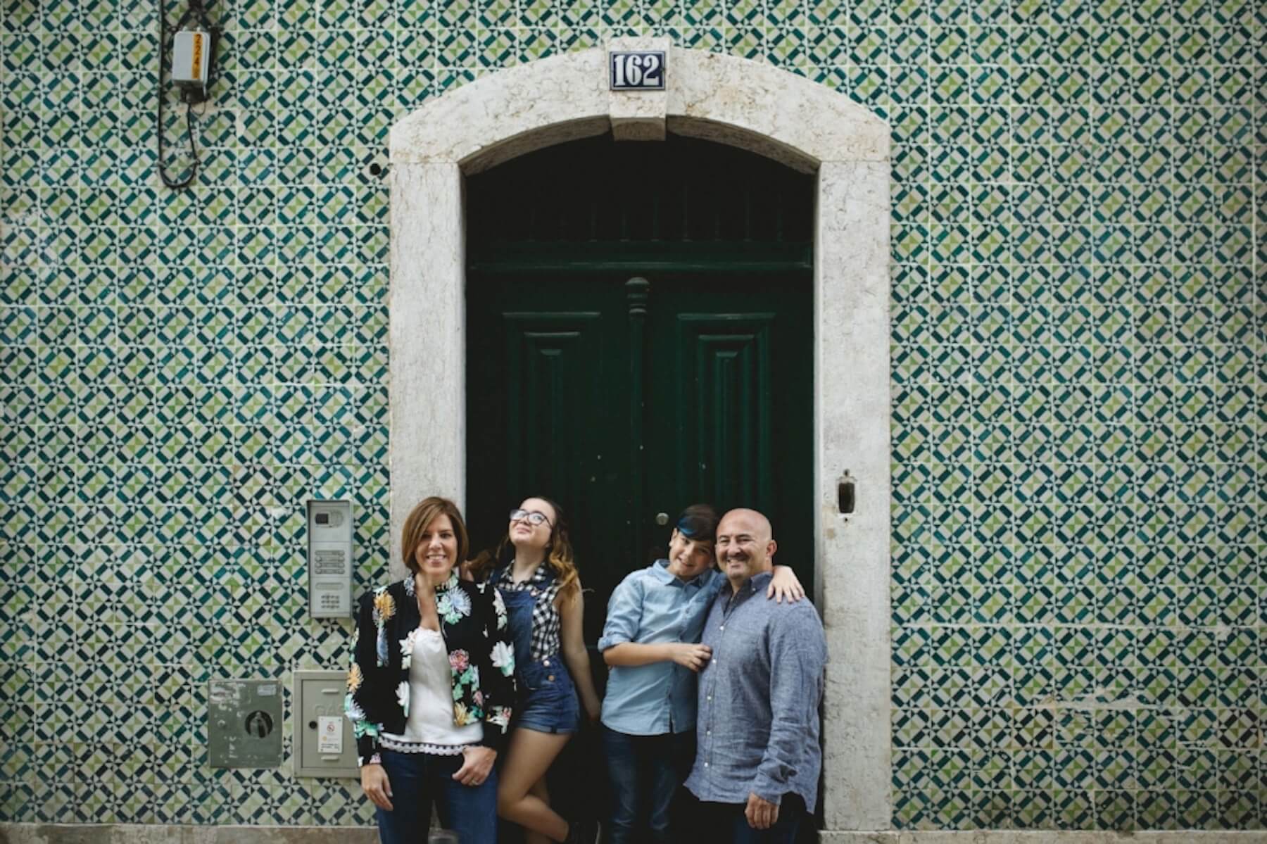 Family of four with two pre-teen children standing in front of building with green and blue Portuguese tile in Lisbon, Portugal