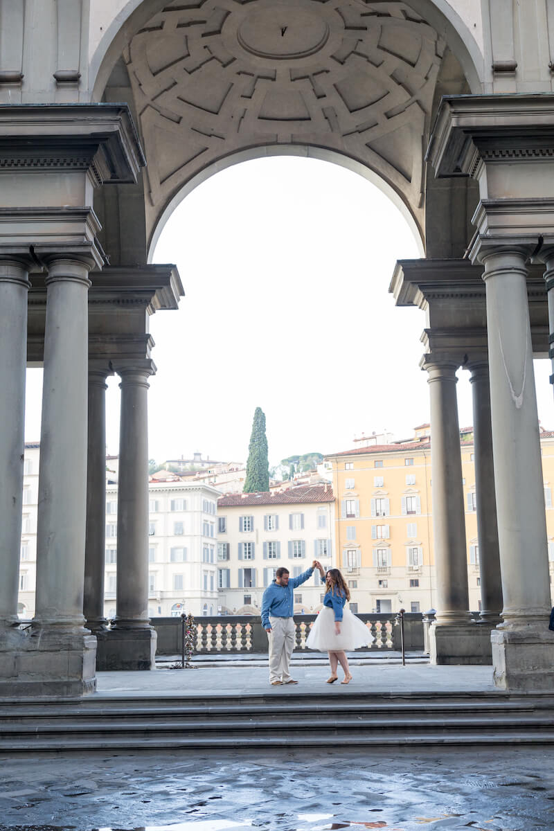 Couple dancing together under archway at Uffizi Gallery in Florence, Italy