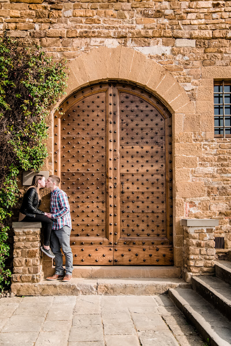 Couple kissing in front of iron studded door in Florence, Italy