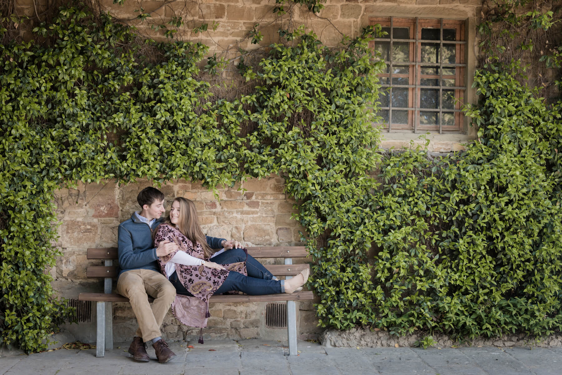 Couple cuddling on bench together with man kissing his partner's cheek in Florence, Italy