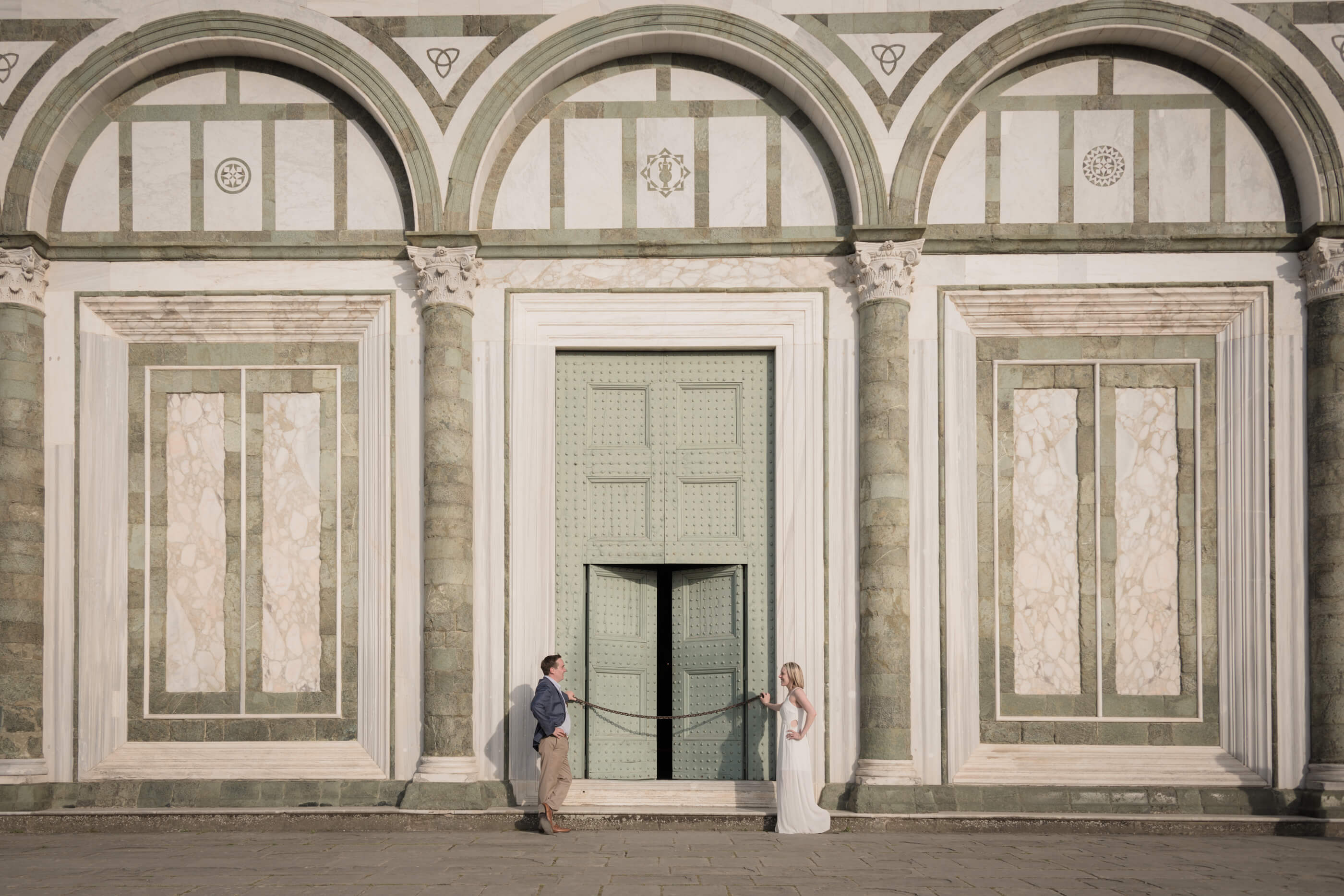 Couple looking at each other in front of The Duomo green door on couples trip in Florence, Italy