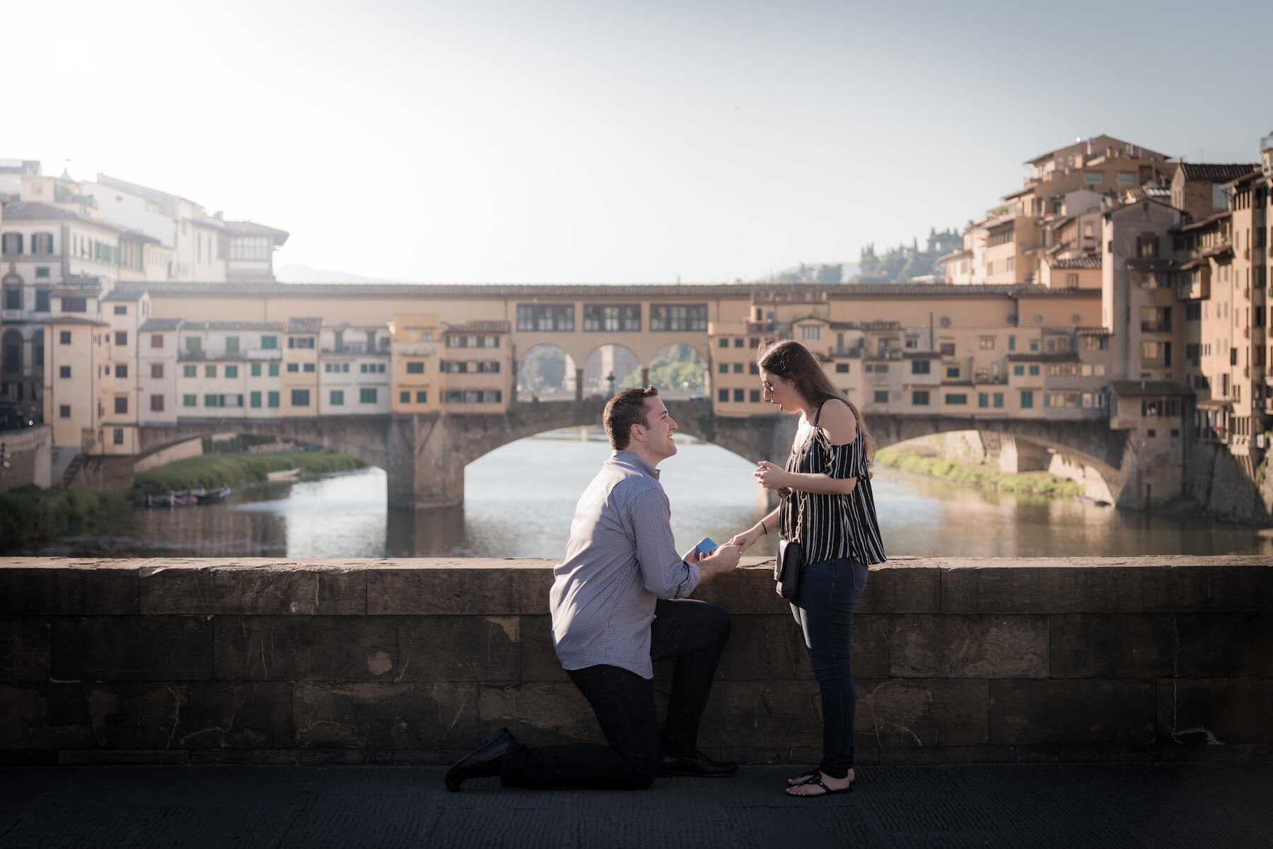 Surprise Flytographer proposal on bridge in front of Ponte Vecchio on couples trip in Florence, Italy