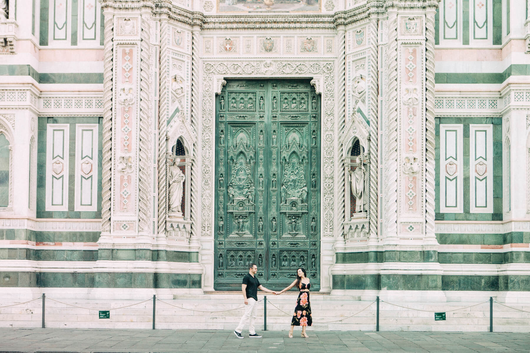 Couple holding hands and walking in front of The Duomo in Florence, Italy
