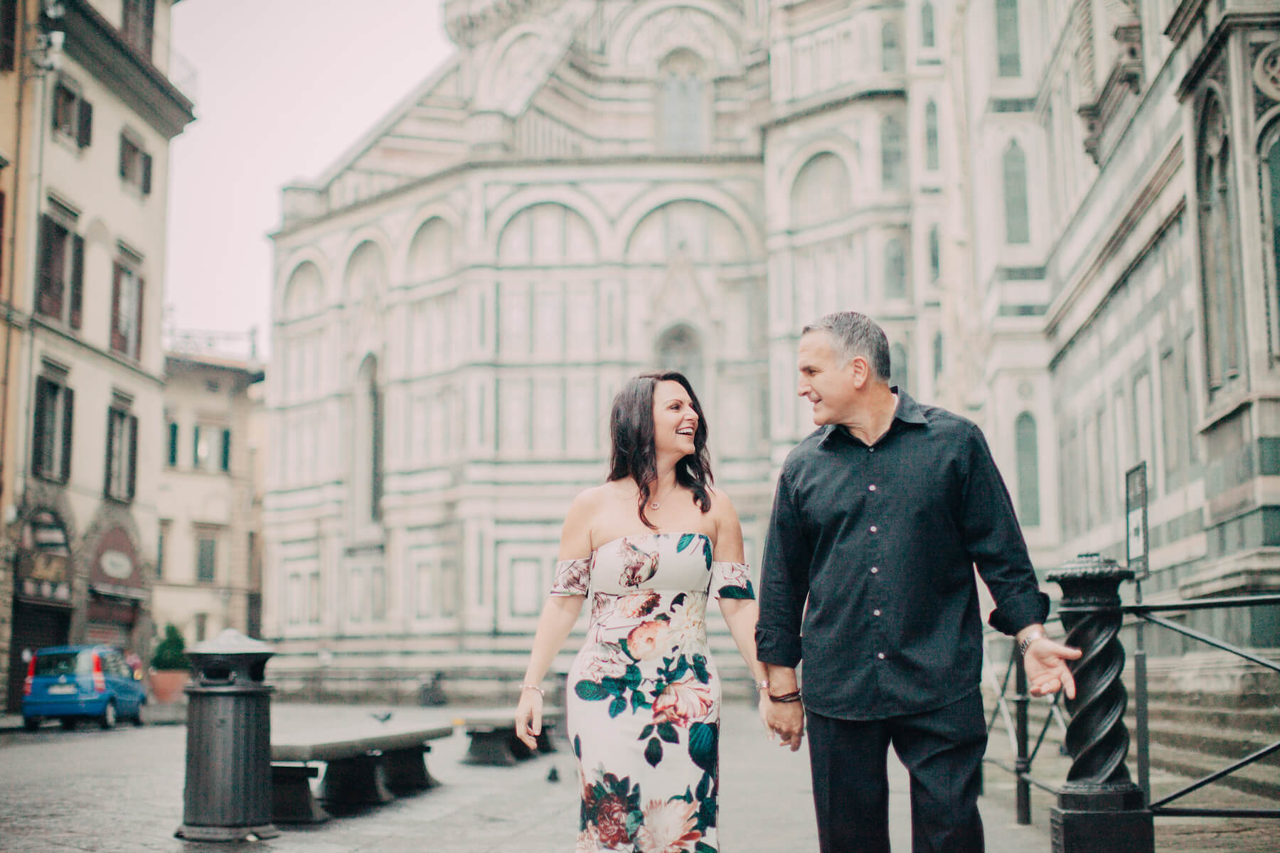 Mature couple holding hands and smiling at each other in front of The Duomo on a couples trip in Florence, Italy