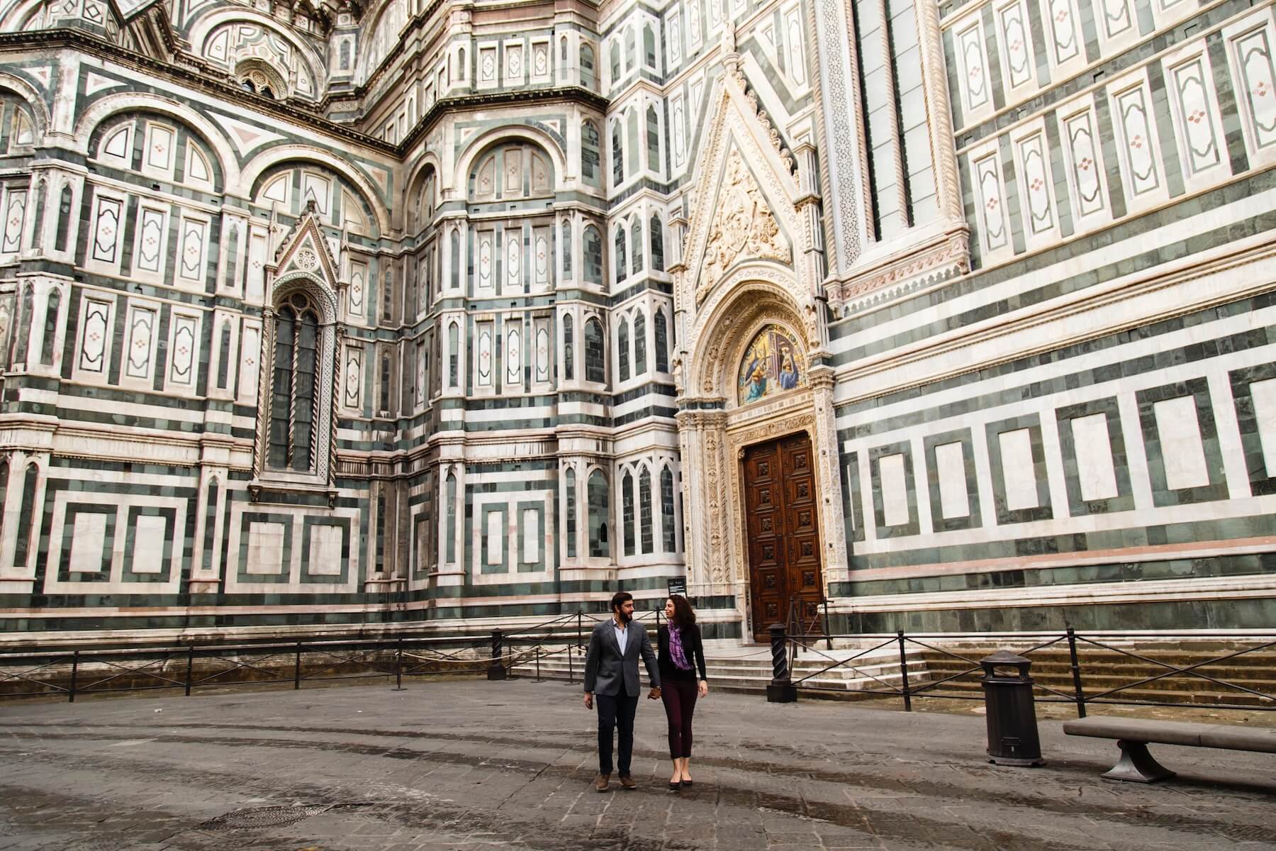 Couple holding hands walking together in front of The Duomo on couples trip in Florence, Italy