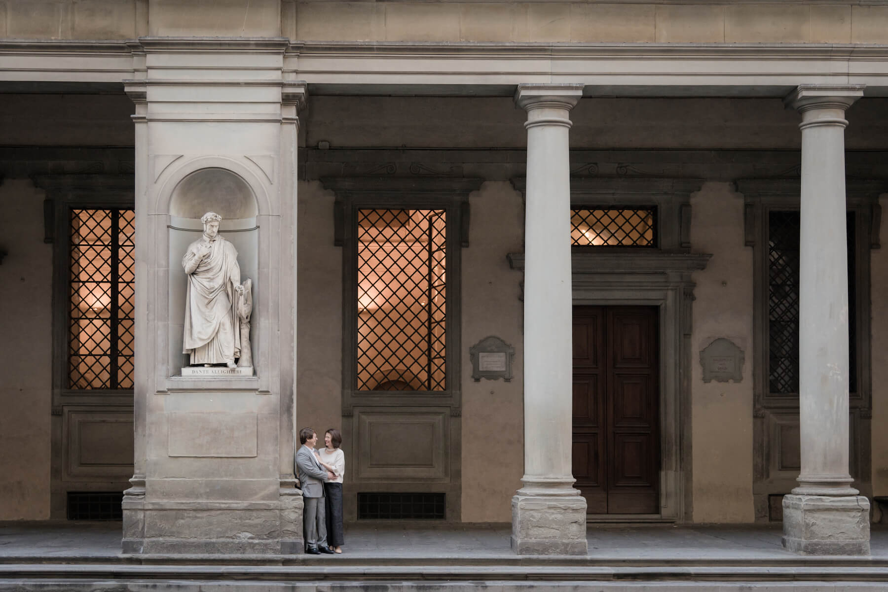 Couple hugging and standing beside the statue of poet Dante Alighieri on a couples trip in Florence, Italy