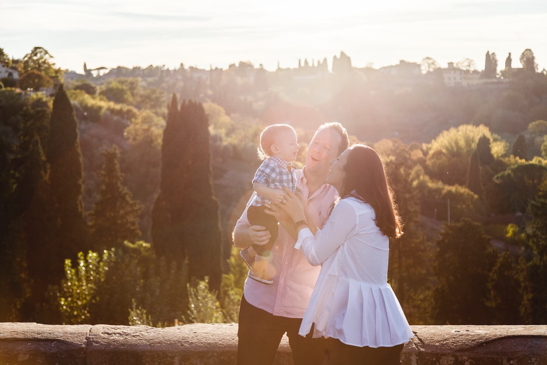 Father and mother holding infant son, all smiling together on a family trip in Florence, Italy