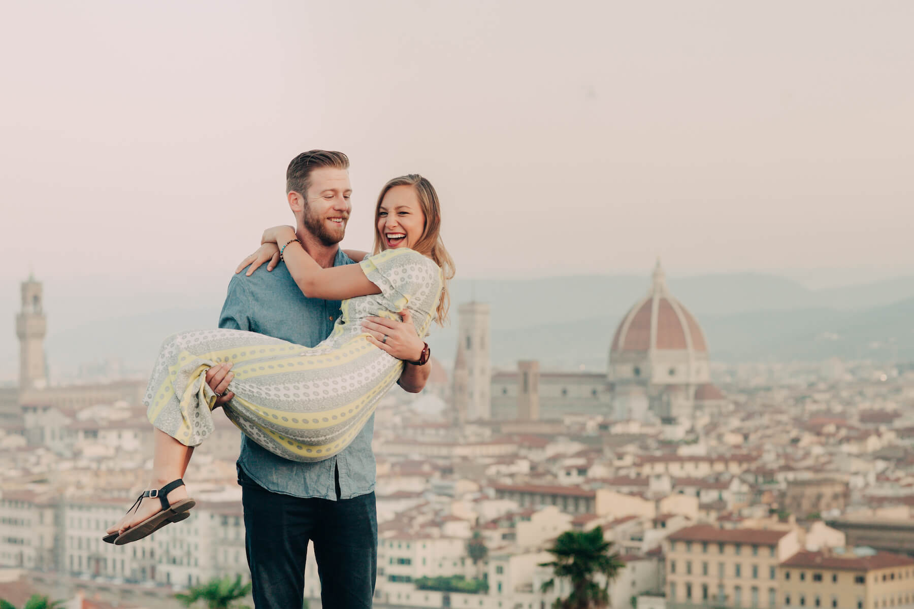 Man holding partner in his arms at Piazzale Michelangelo in Florence, Italy