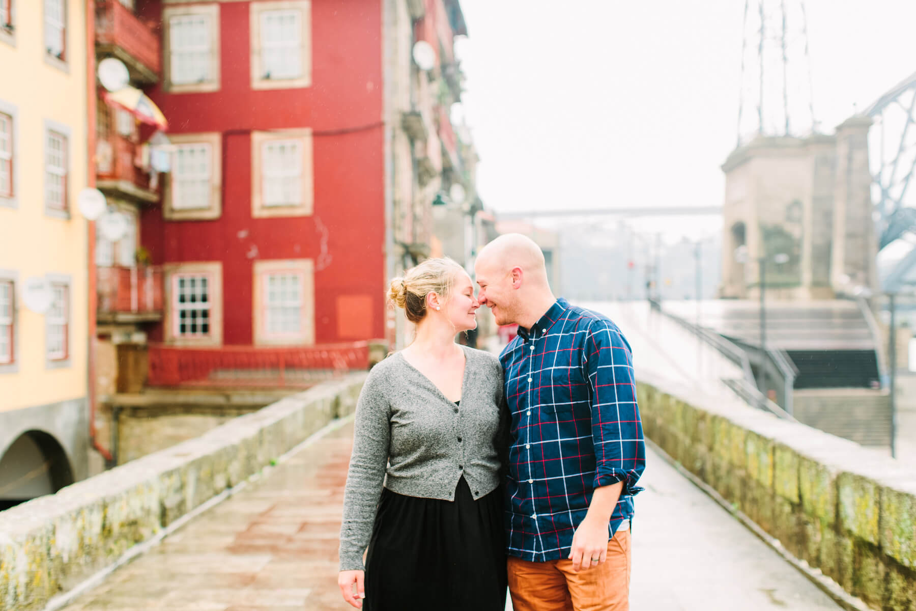 Couple smiling at each other on a bridge walkway on a couples trip in Porto, Portugal
