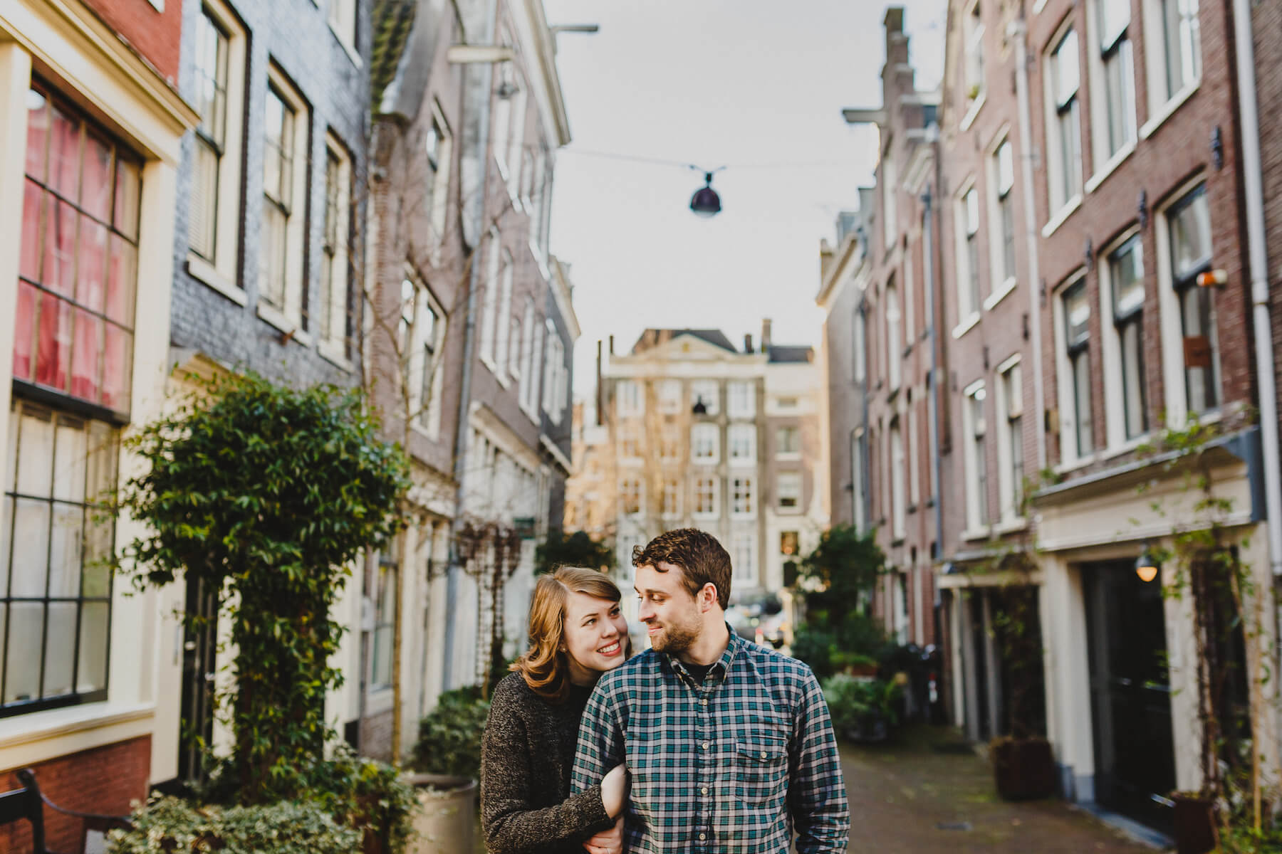 Couple looking at each other lovingly while standing in a small alleyway in Amsterdam, Netherlands