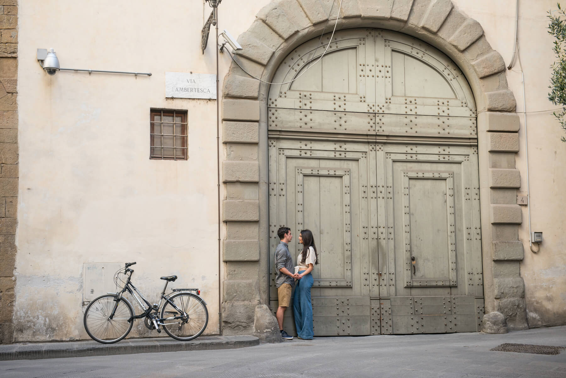 Couple standing together in front of large doorway in Florence, Italy
