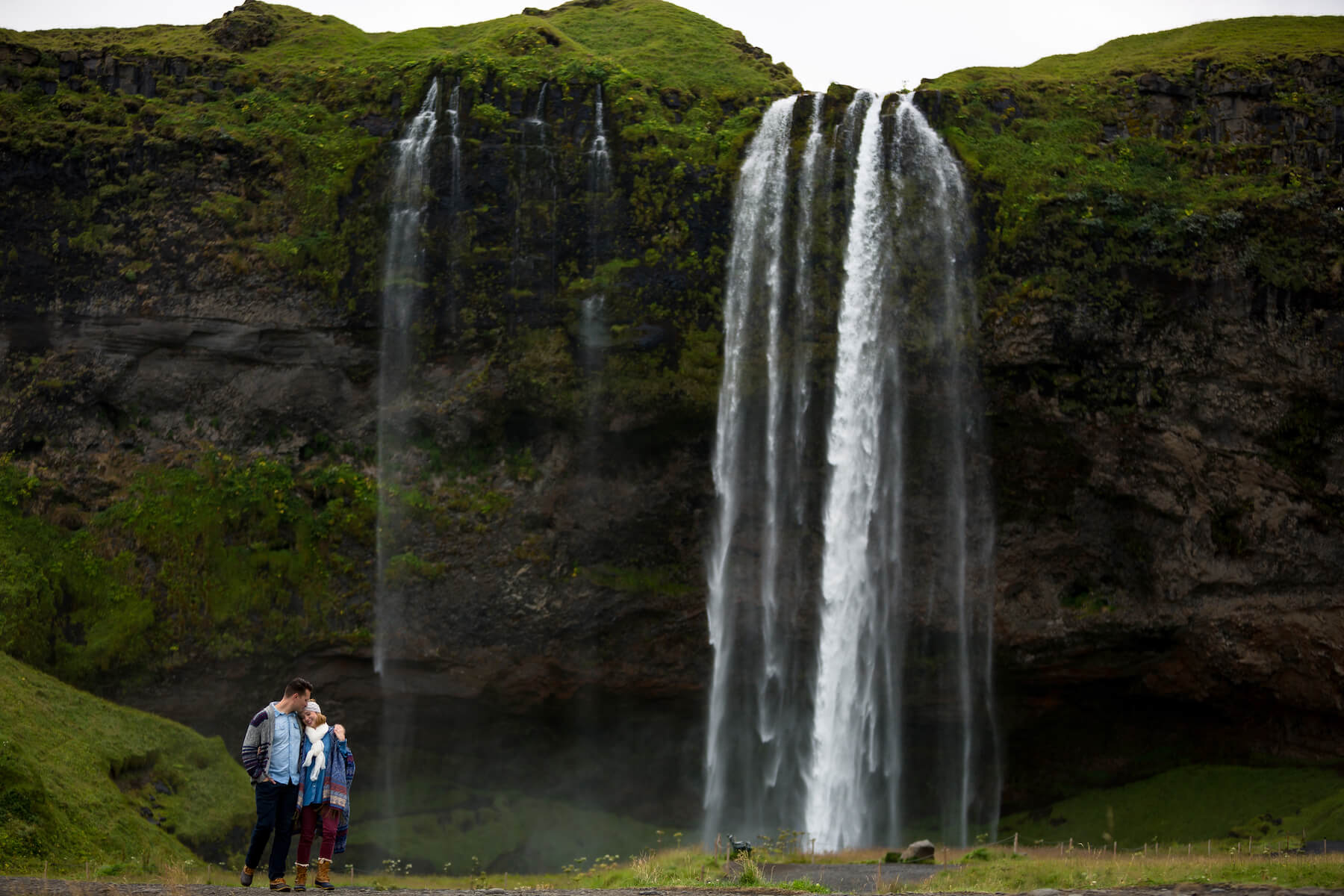 Couple hugging each other in front of waterfall in Reykjavik, Iceland