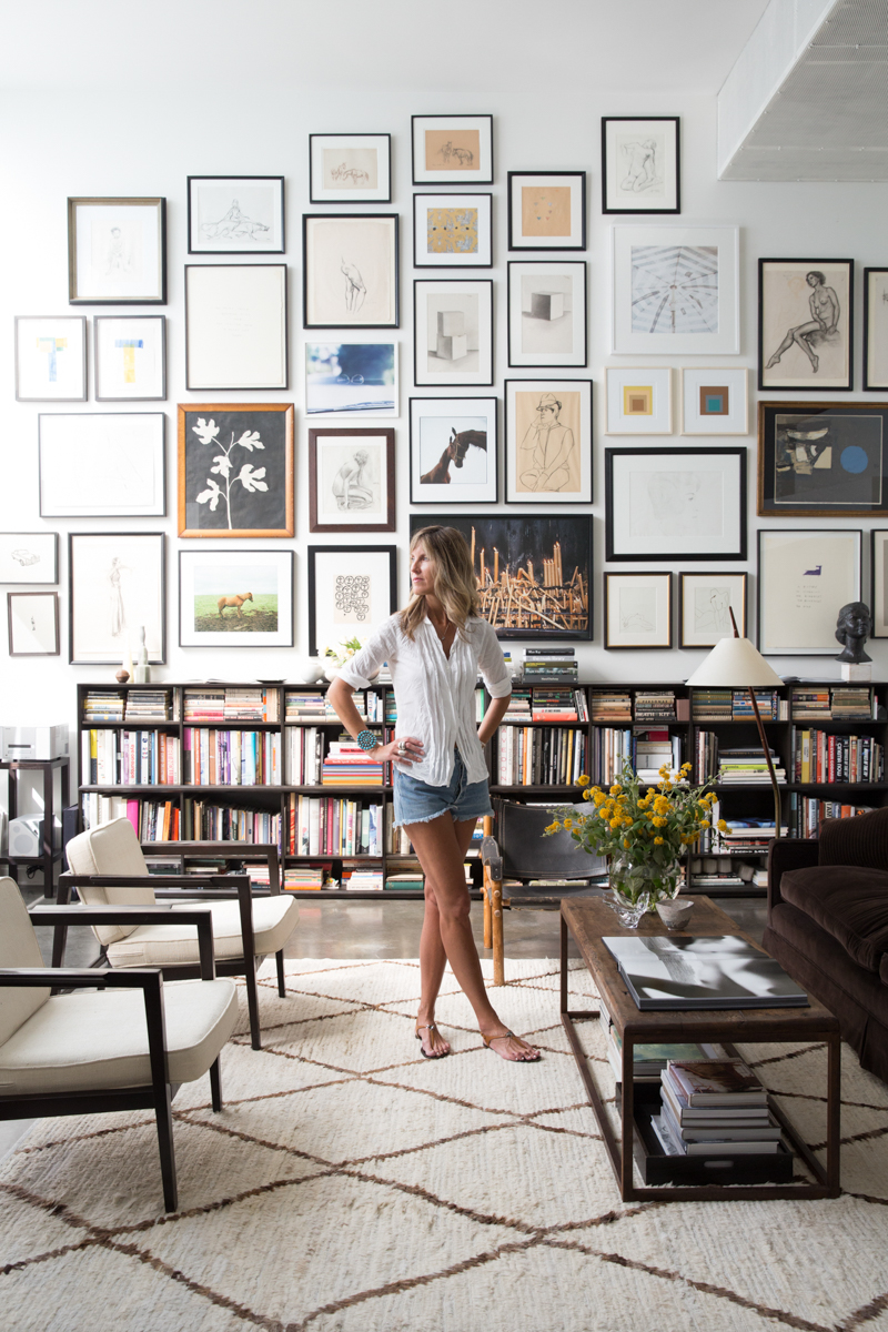 Woman standing in living room surrounded by artwork