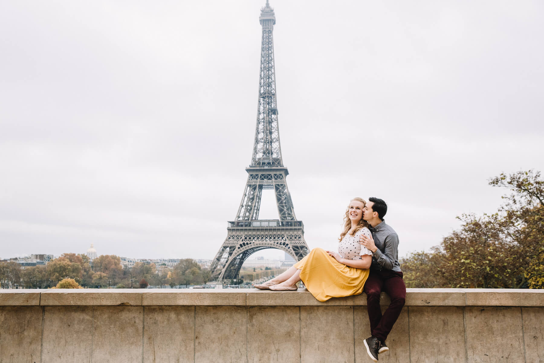 Couple holding each other and kissing with the Eiffel Tower in the background in Paris, France