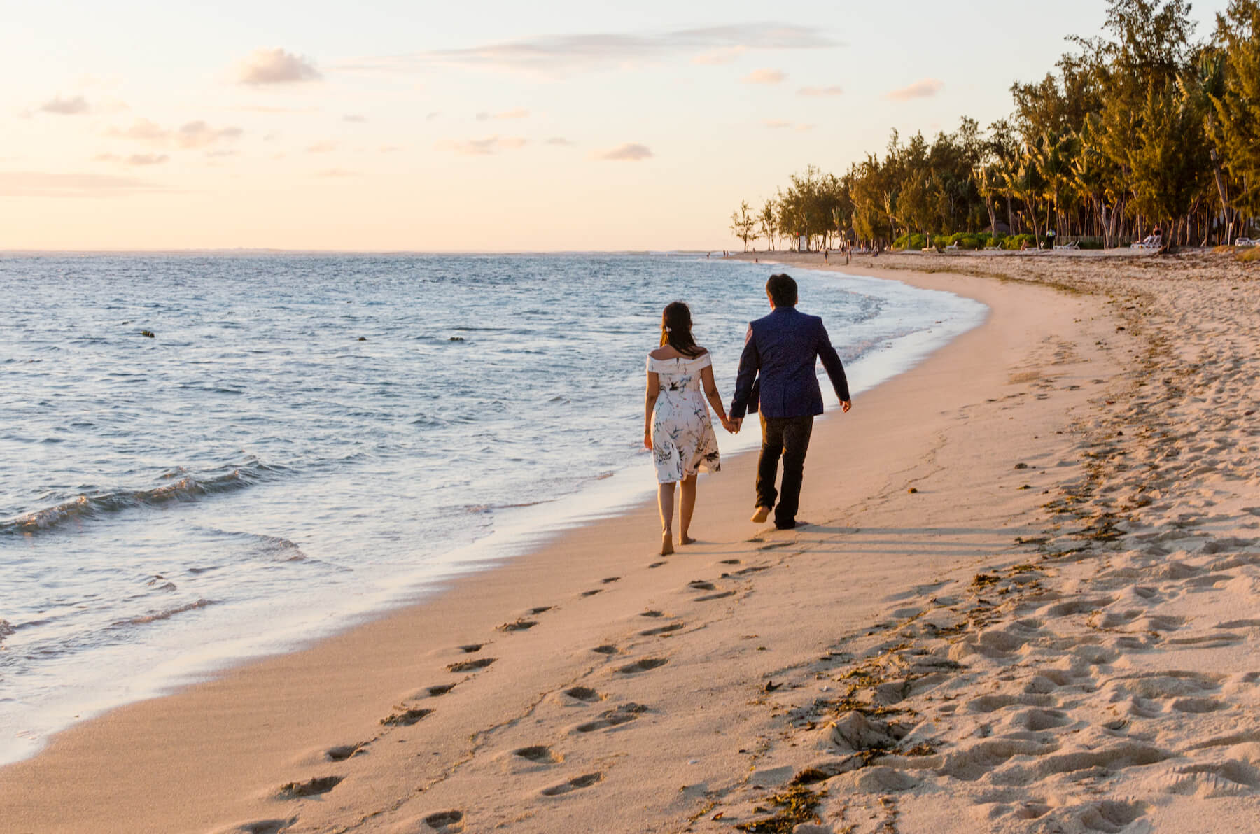 Couple holding hands and walking down the beach together at sunset in Mauritius