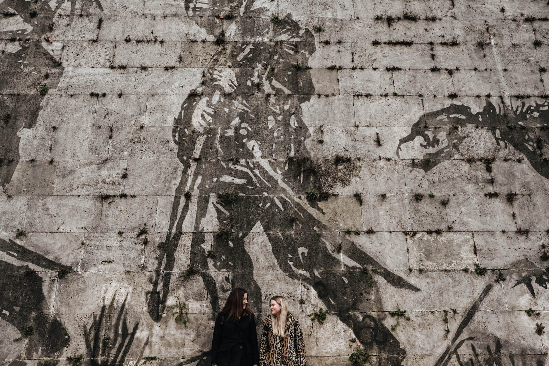 Sisters standing against a feature wall together on a family trip in Rome, Italy
