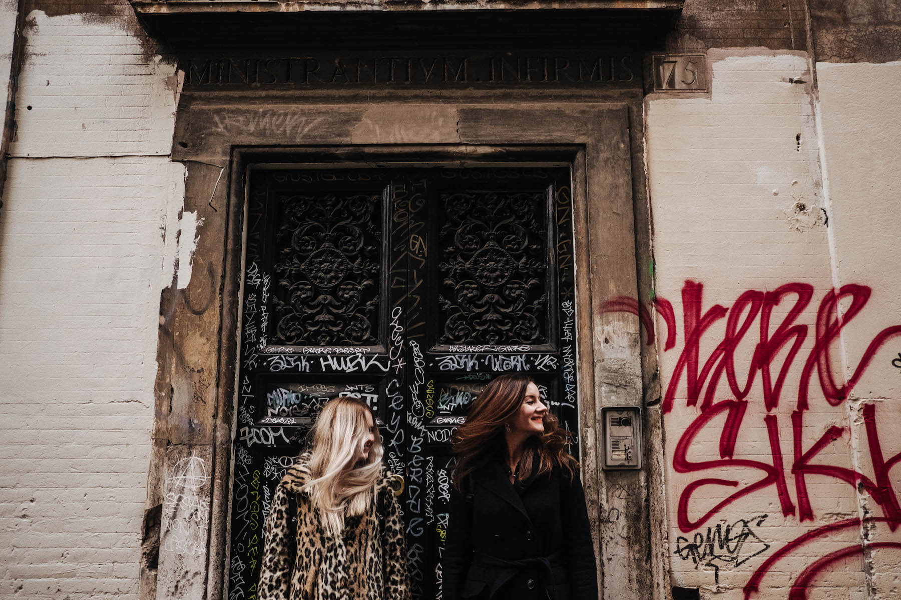 Sisters standing against a feature graffitti doorway together on a family trip in Rome, Italy