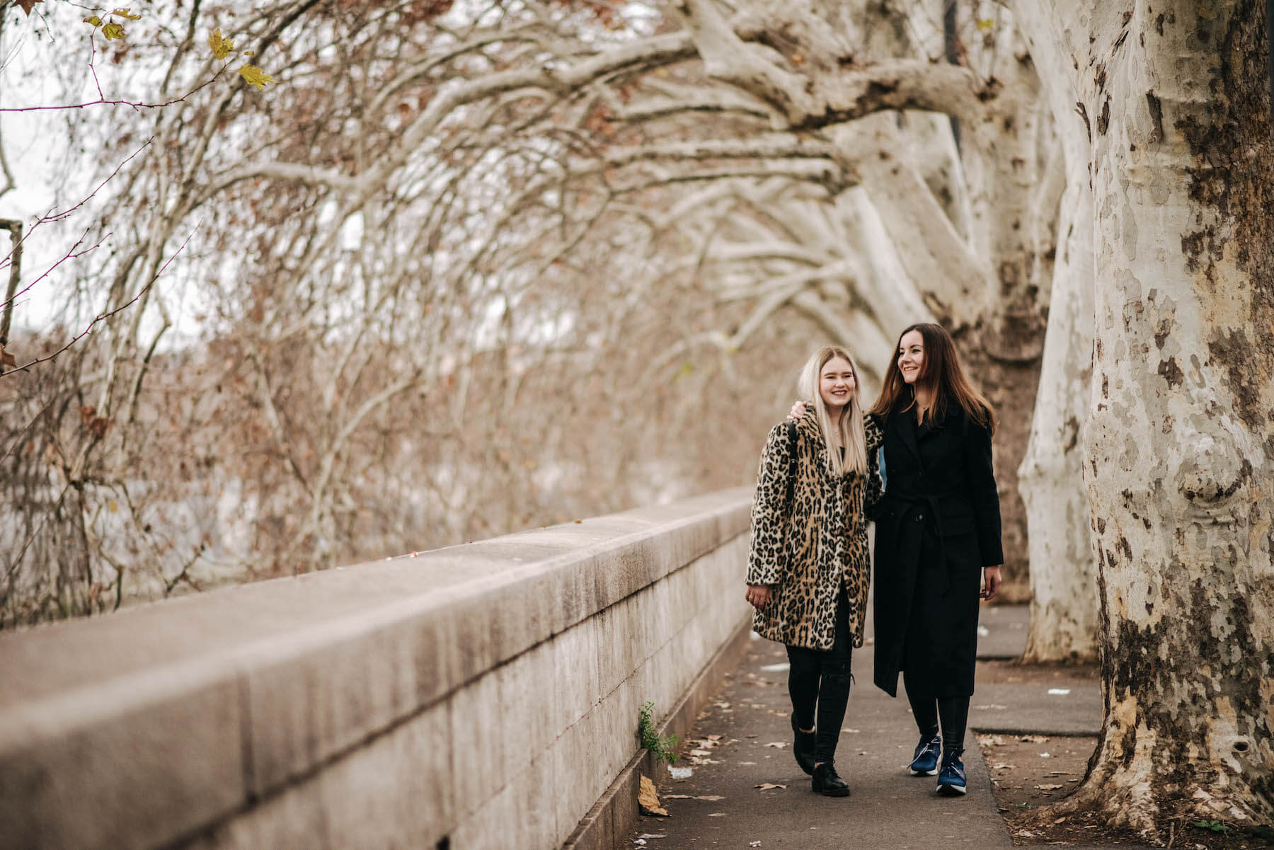 Sisters standing together on walkway in autumn on a family trip in Rome, Italy