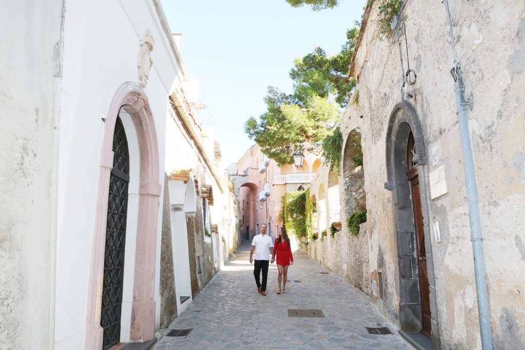A couple walks down a narrow cobblestone street in the Amalfi Coast.