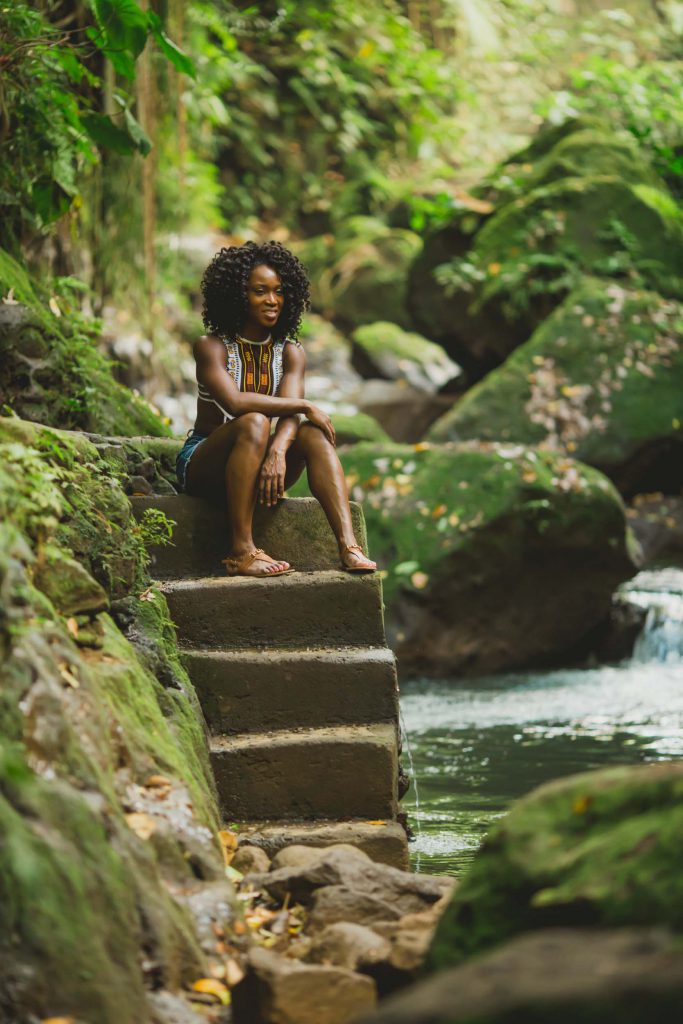A woman sits in Bali surrounded by lush green plants.