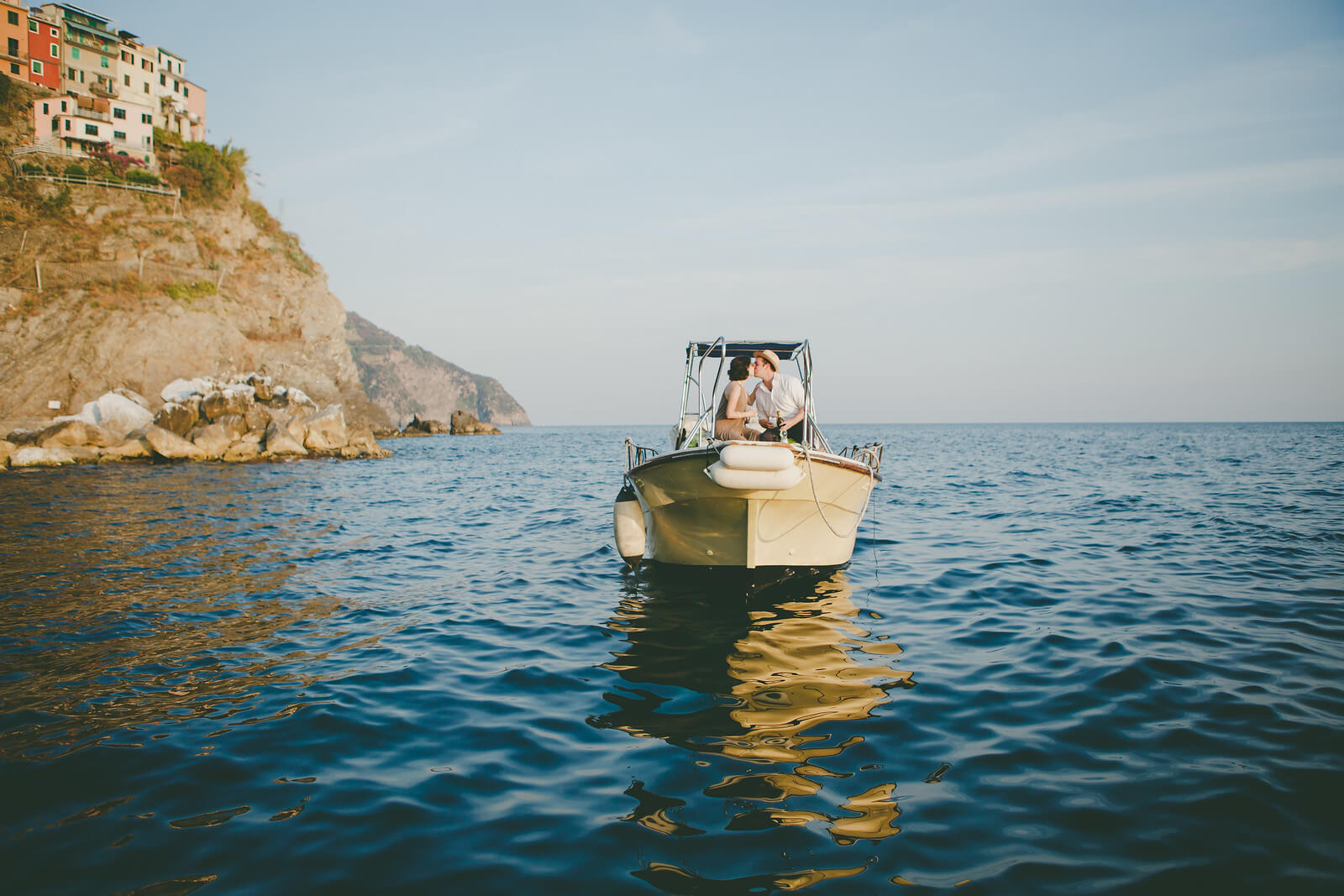 Two people kissing on a small boat in the waters of Cinque Terre, Italy
