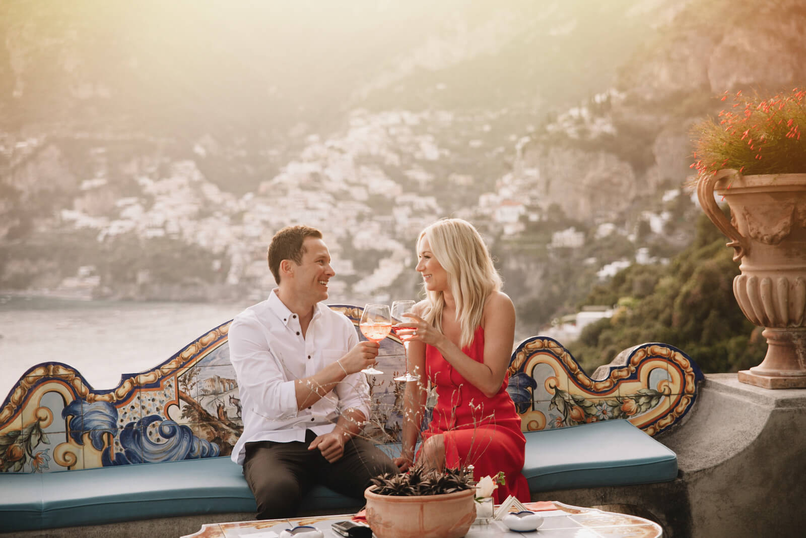 Couple toasting wine glasses together at sunset in Amalfi Coast, Italy