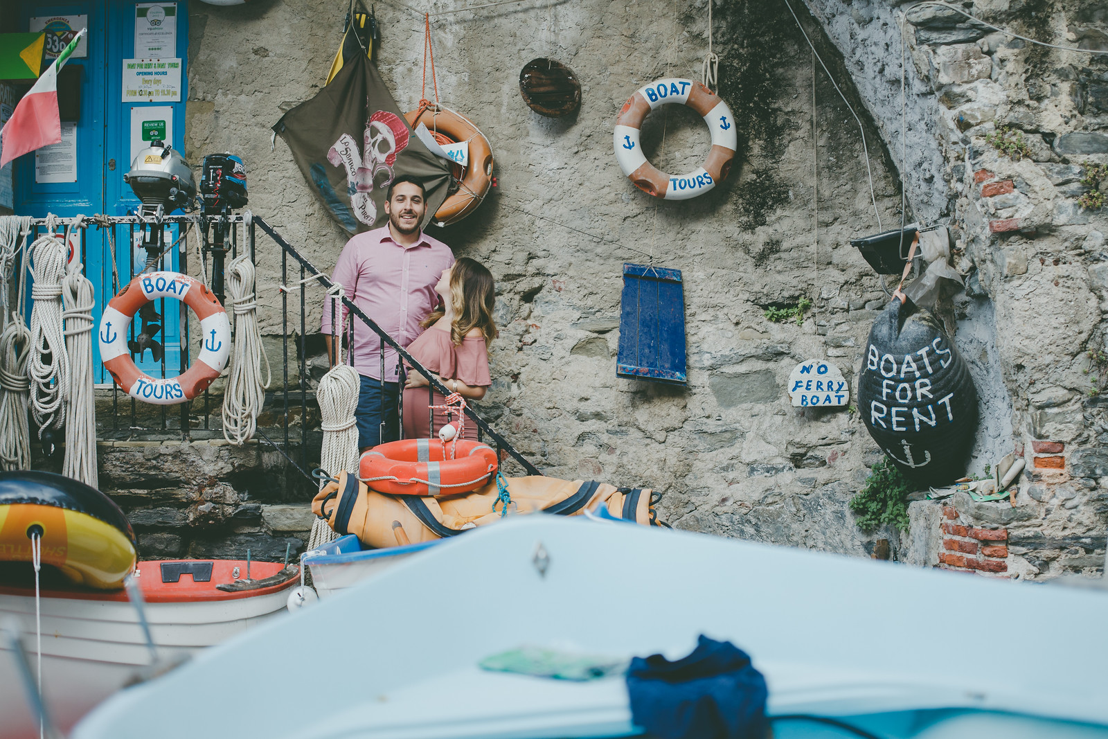 Couple standing on staircase surrounded by fishing materials in Cinque Terre, Italy