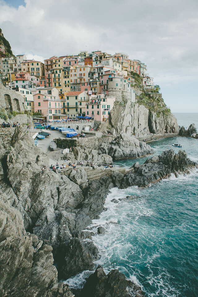 Cinque Terre coastline in Italy with a group of people sitting along the rocky shoreline