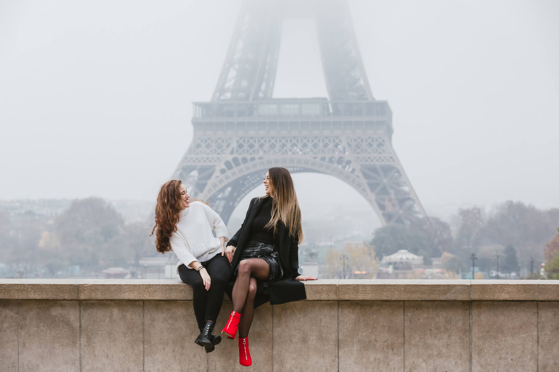 Friends sitting together in front of the Eiffel Tower in Paris, France