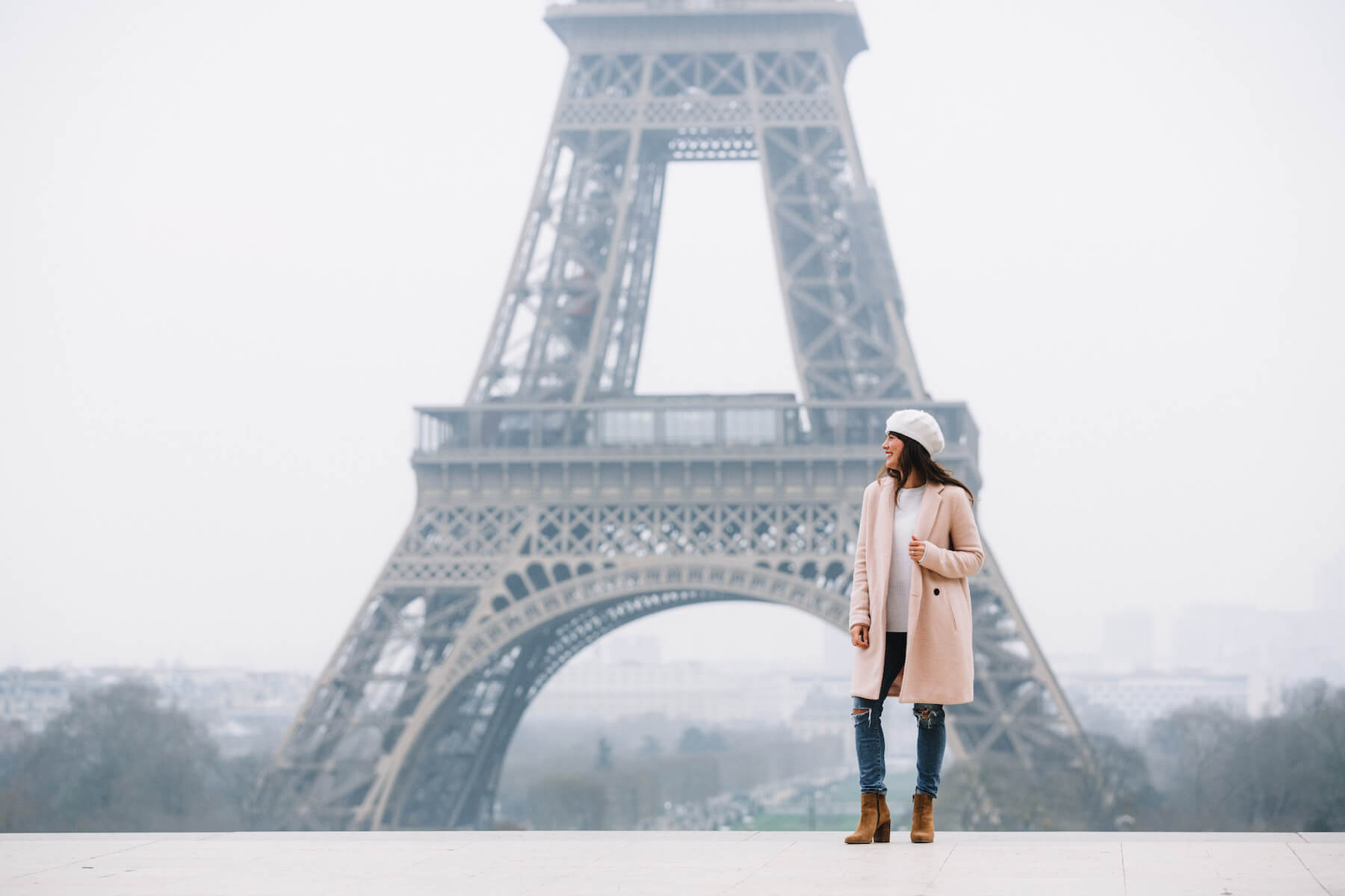 Woman smiling with the Eiffel Tower in the background on a solo photo shoot in Paris, France