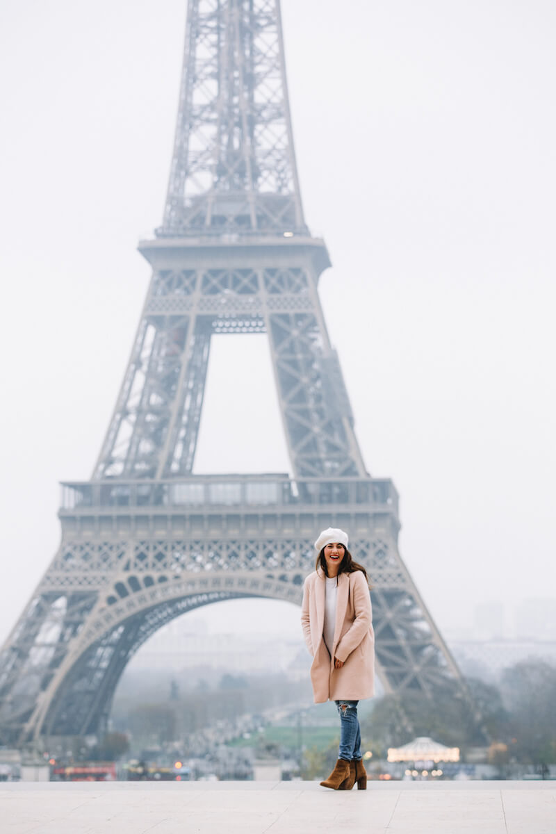Woman smiling with the Eiffel Tower in the background on a solo photo shoot in Paris, France