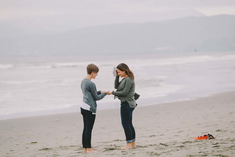 LGBTQ+ couple, woman proposing to her partner and putting the engagement ring on her finger in San Francisco, USA