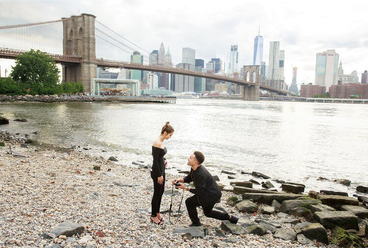Man proposing to his partner on a pebble beach in Brooklyn, New York City USA