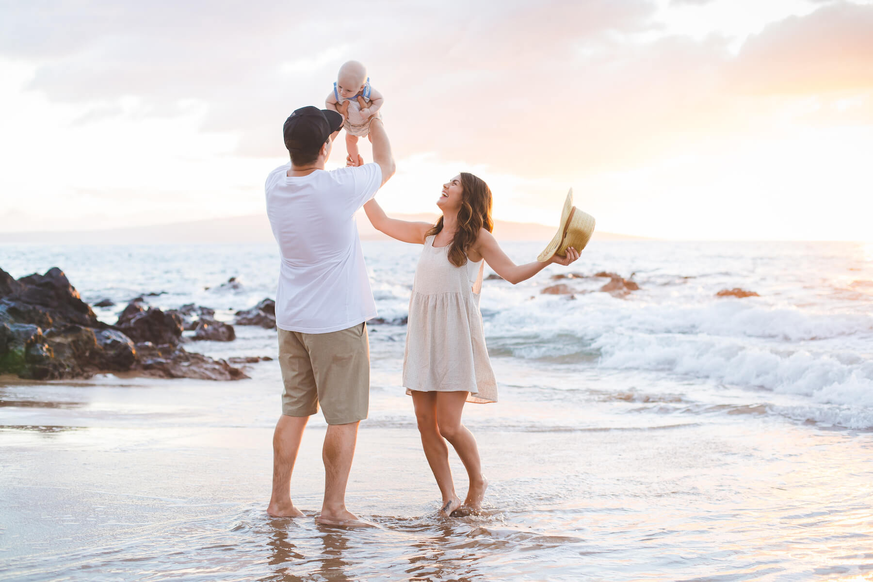 family on the beach holding their baby up in the air in Maui, Hawaii