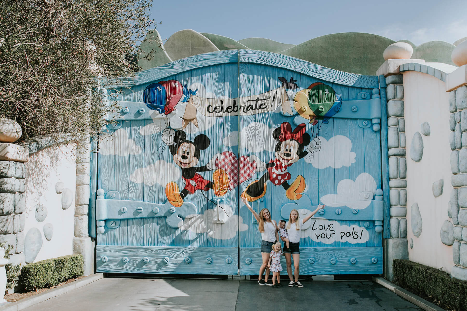 LGBTQ+ family with two young kids standing in front of a colourful door at Disneyland, Anaheim, California USA
