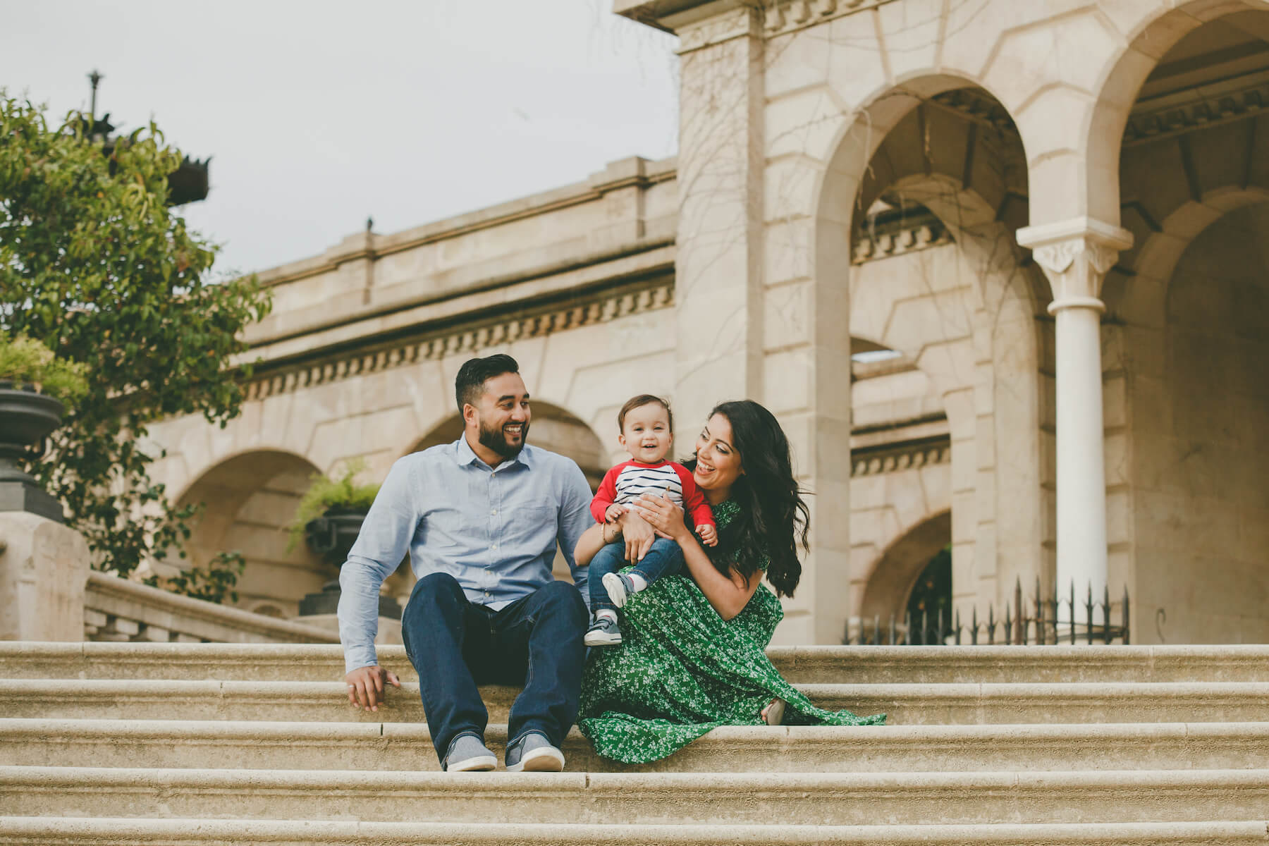 a family with a young child sitting on the steps in Barcelona, Spain