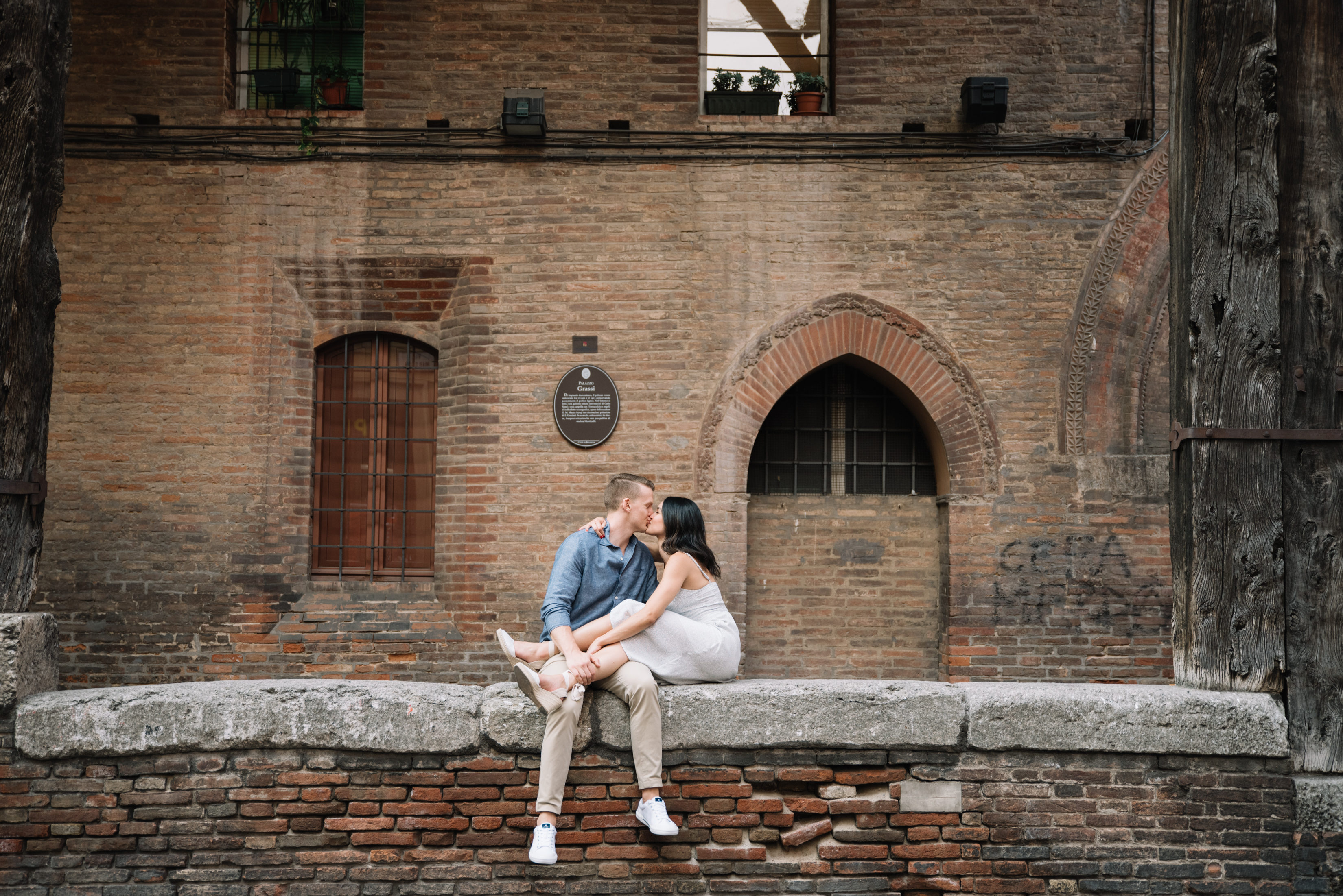 couple sitting on a ledge, kissing, in Bologna, Italy