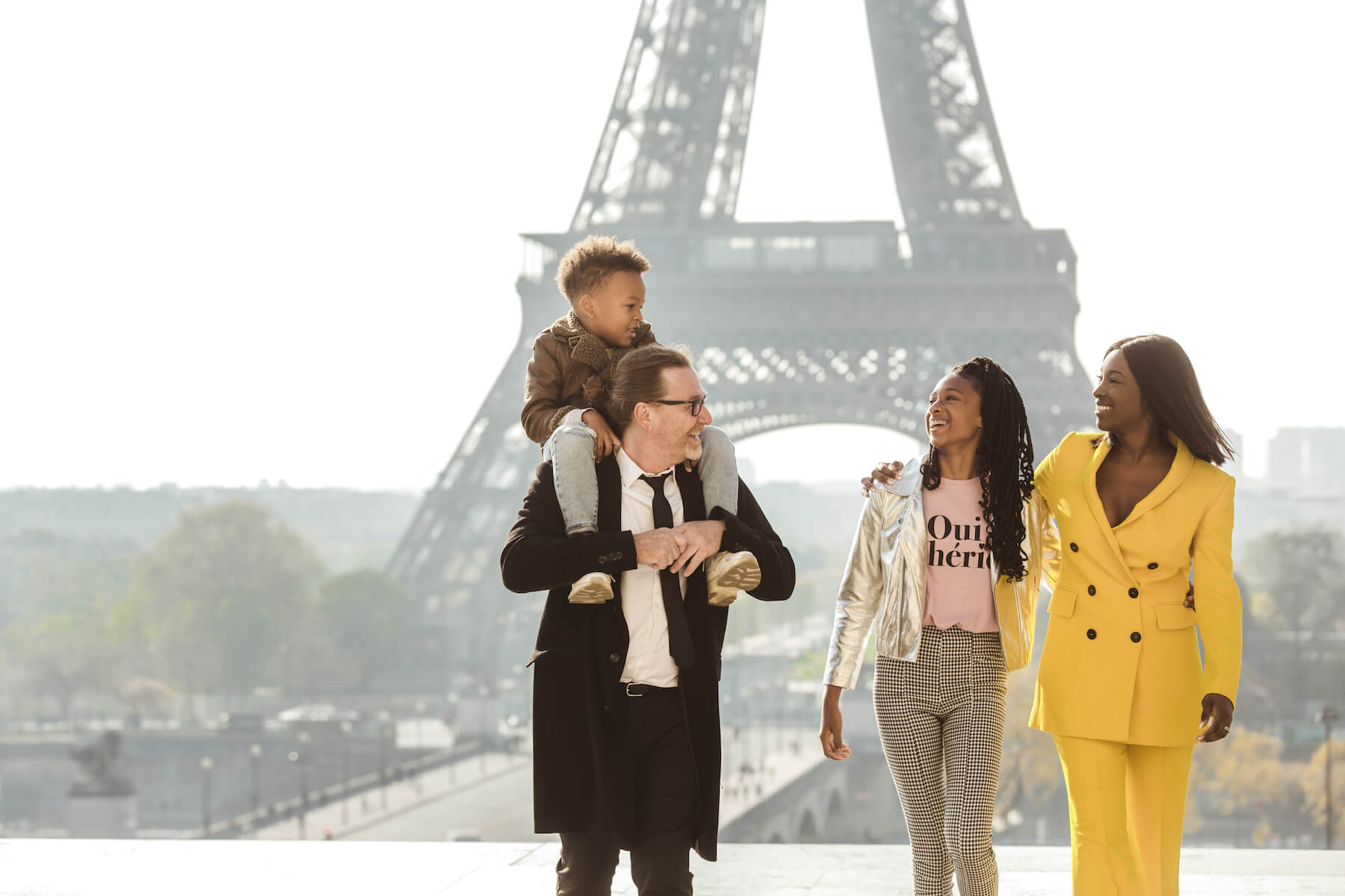 a family of four standing and walking with the Eiffel tower in the background in Paris, France