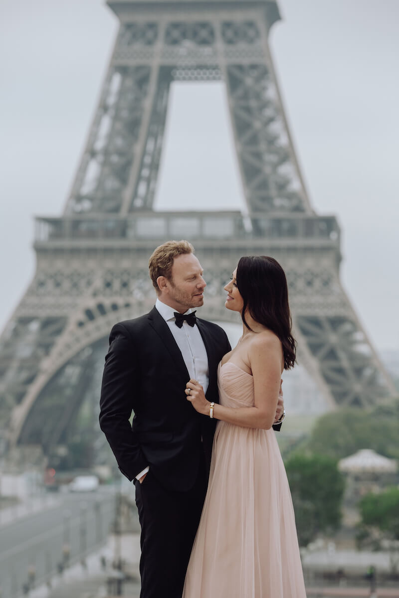 Couple holding each other in front of the Eiffel tower in Paris France