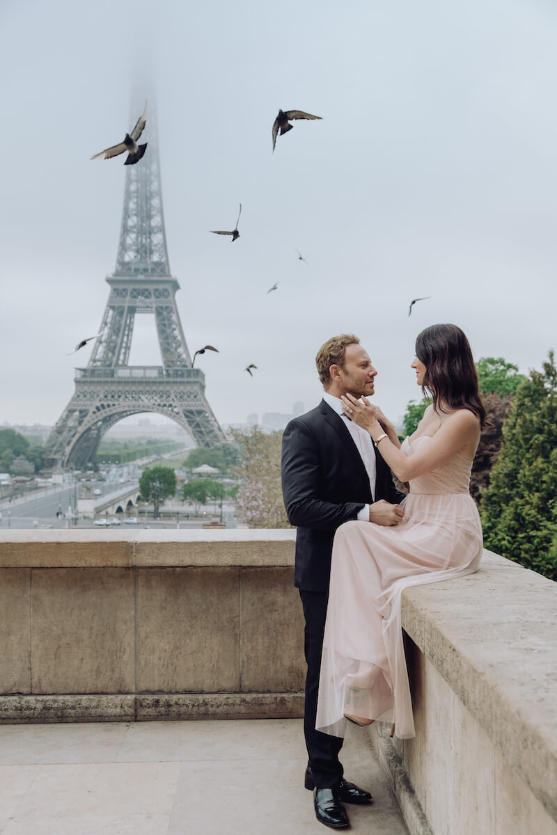 couple in front of Eiffel tower fixing bow tie in Paris France