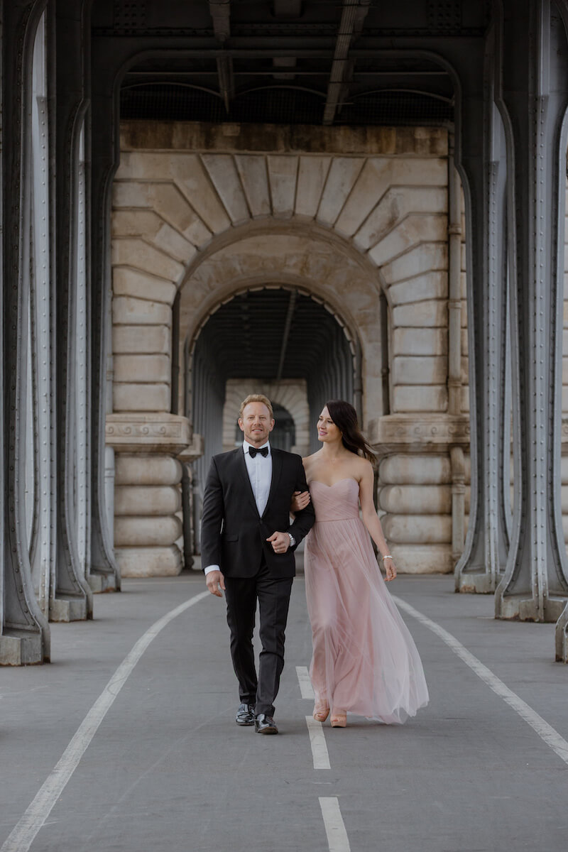 Couple holding arms walking under the bridge in Paris France