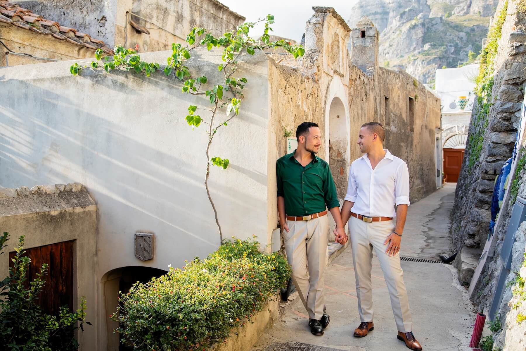 LGBTQ couple holding hands and standing in a small cobble street in Amalfi Coast, Italy