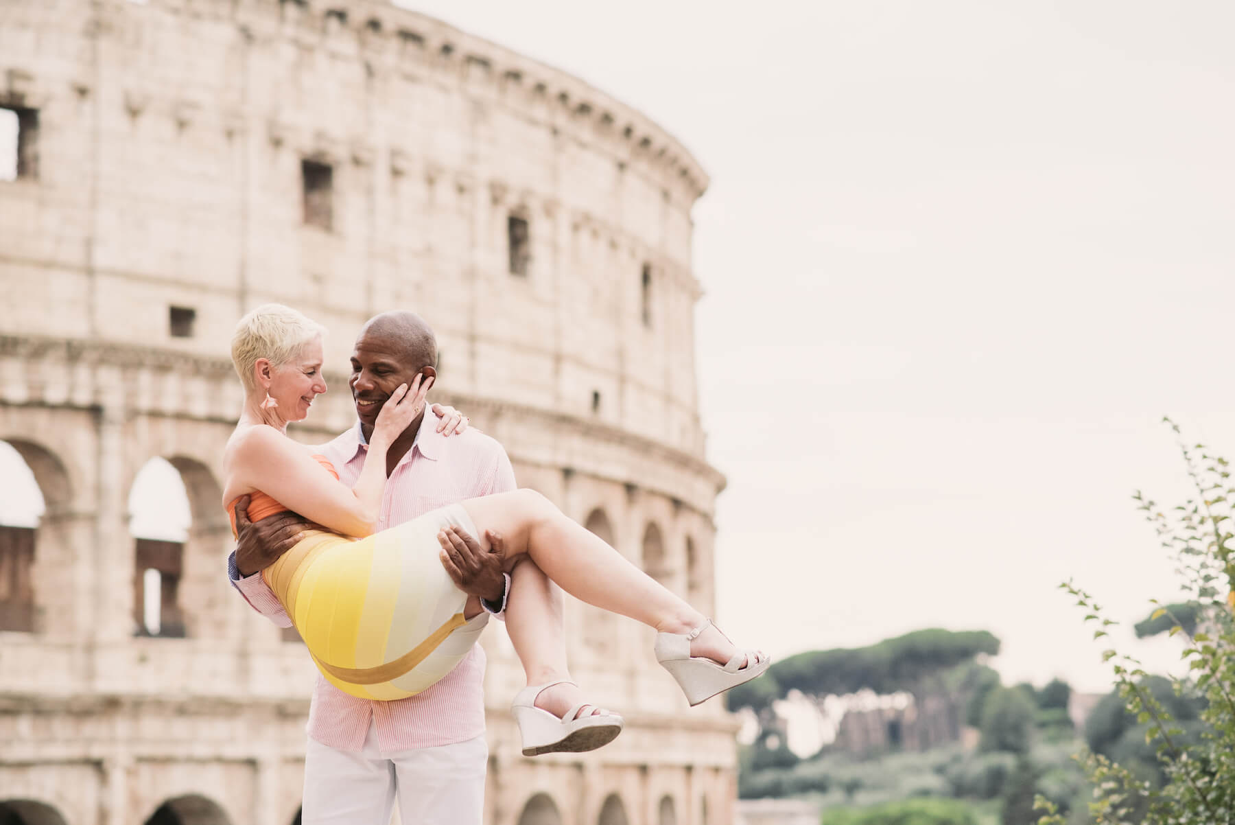 couple standing in front of the Colosseum, the man is holding the lady in Rome, Italy