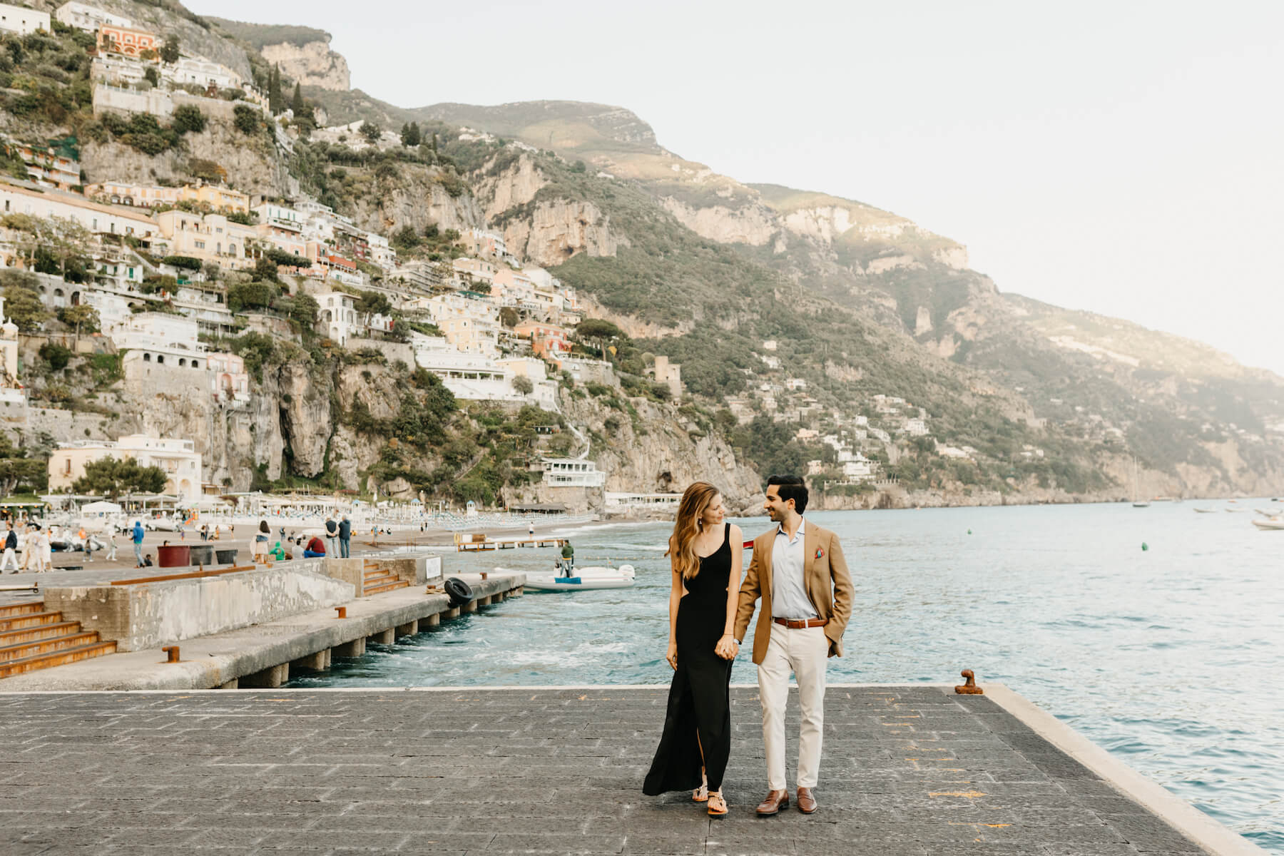 couple holding hands and walking on the beach in Positano, Italy