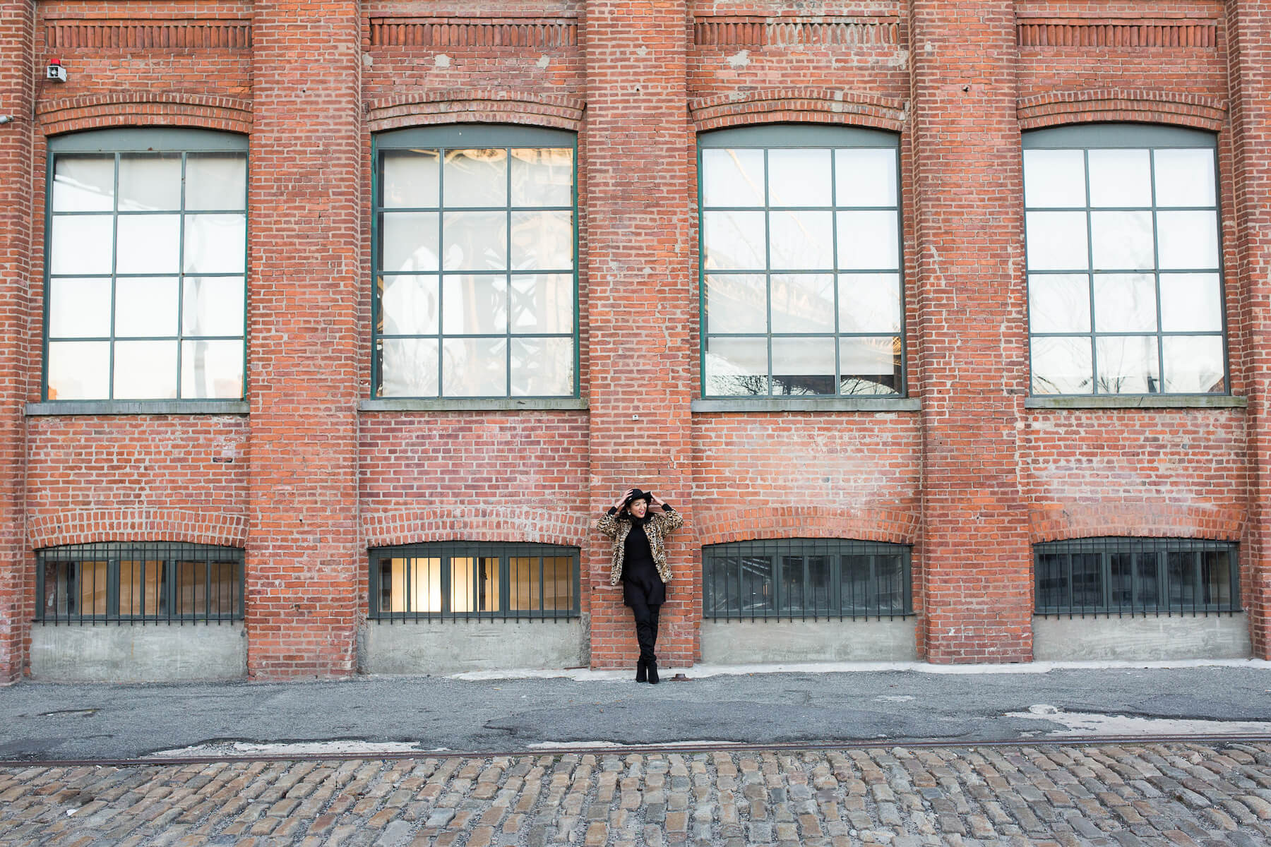 woman solo traveller standing against brick wall in New York City